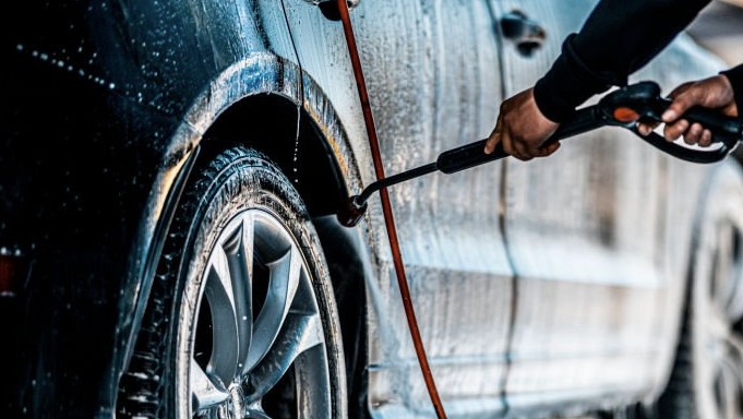 Customer using the car wash wand at Marcy Car Wash